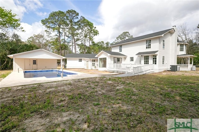 back of property with central AC unit, an outdoor pool, a lawn, a chimney, and an outdoor structure