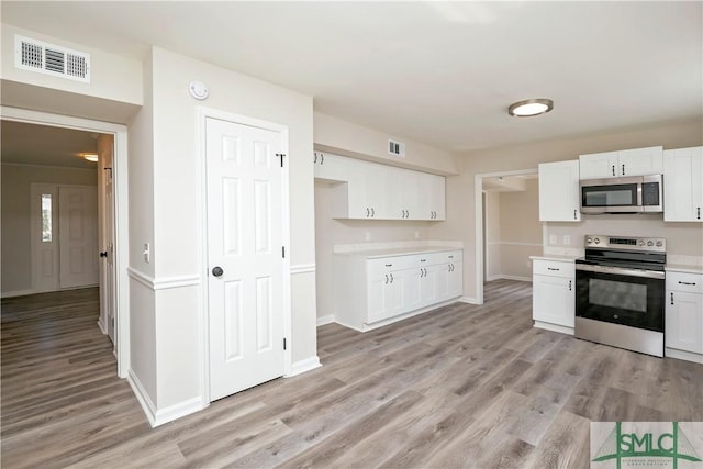 kitchen with appliances with stainless steel finishes, visible vents, and white cabinetry