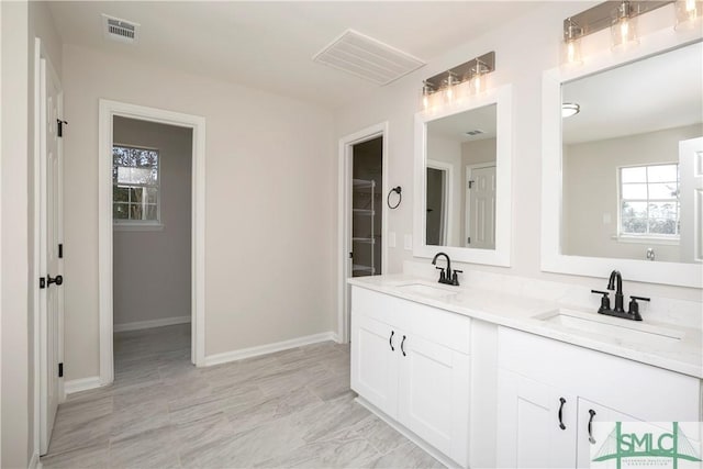 bathroom featuring double vanity, a sink, visible vents, and baseboards