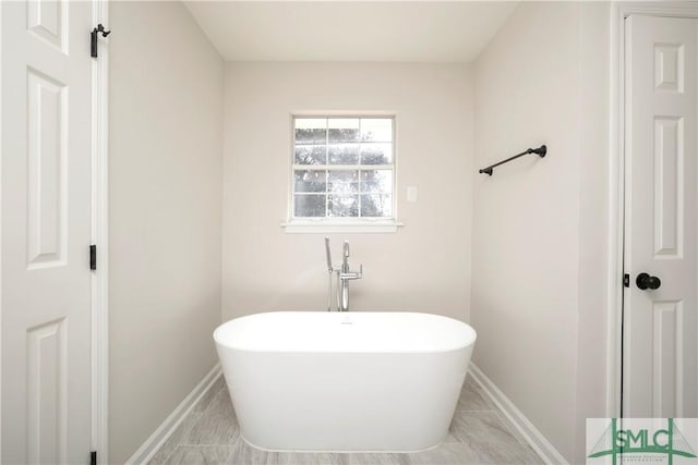 bathroom with a freestanding tub and baseboards