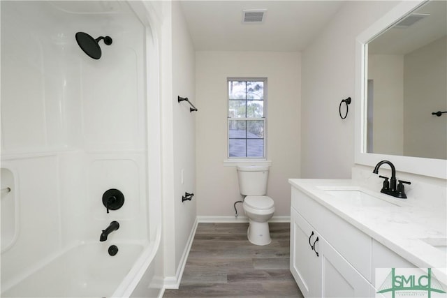 bathroom with toilet, wood finished floors, vanity, visible vents, and tub / shower combination