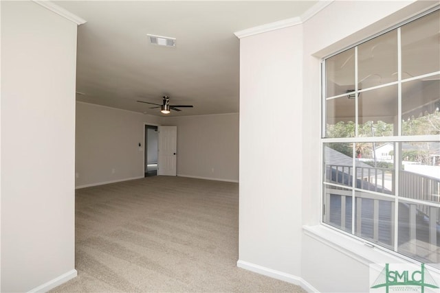 carpeted empty room featuring ornamental molding, visible vents, ceiling fan, and baseboards