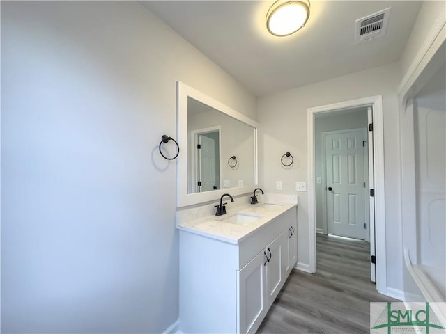 bathroom with double vanity, visible vents, a sink, and wood finished floors