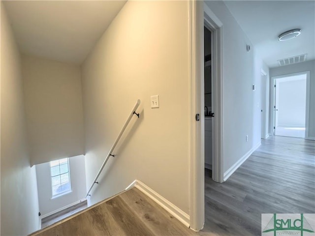 staircase featuring visible vents, baseboards, and wood finished floors