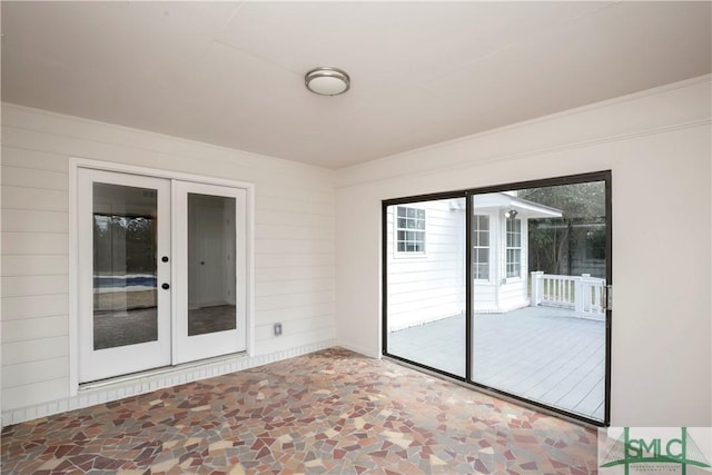 empty room with wooden walls, stone finish floor, and french doors