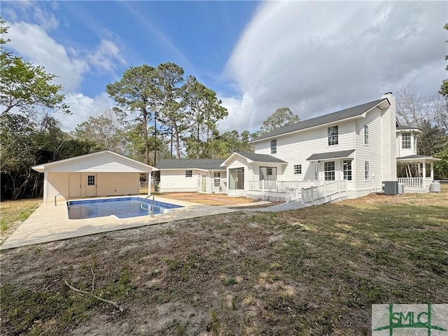 rear view of house with an outdoor pool, a patio, a chimney, a yard, and central air condition unit