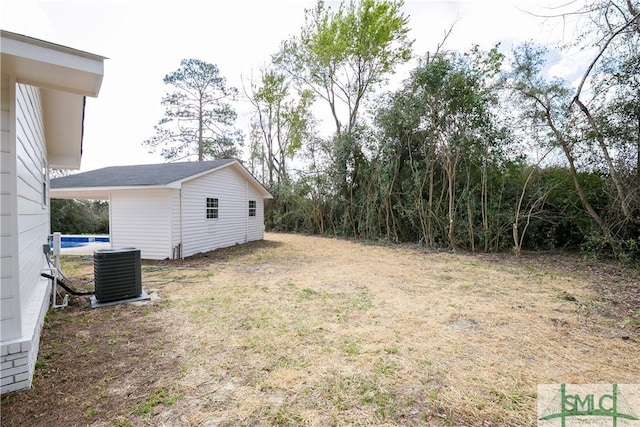 view of yard featuring an outbuilding, a swimming pool, and central air condition unit