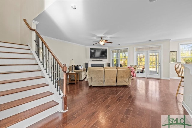 living area featuring dark wood-type flooring, a fireplace, stairway, and ornamental molding