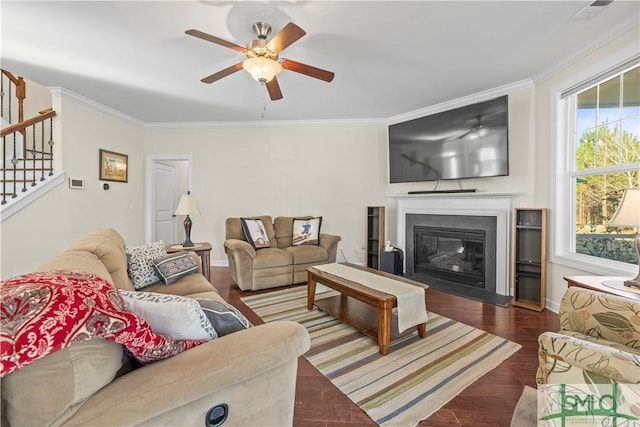 living area featuring ornamental molding, a glass covered fireplace, stairs, and wood finished floors