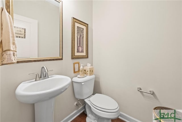 bathroom featuring a sink, wood finished floors, toilet, and baseboards