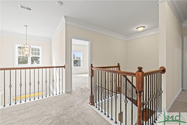 corridor featuring carpet floors, a notable chandelier, crown molding, visible vents, and an upstairs landing