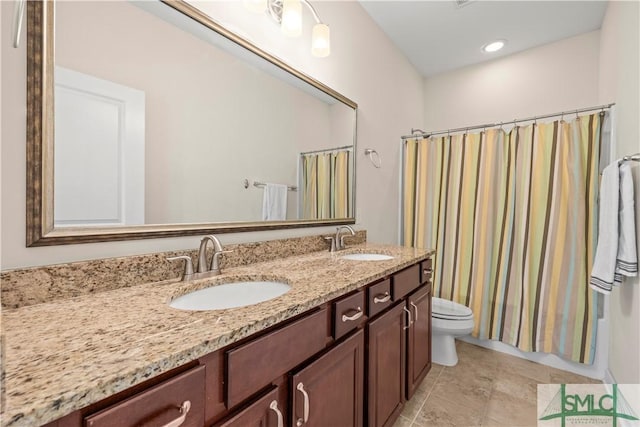 bathroom with double vanity, tile patterned flooring, toilet, and a sink