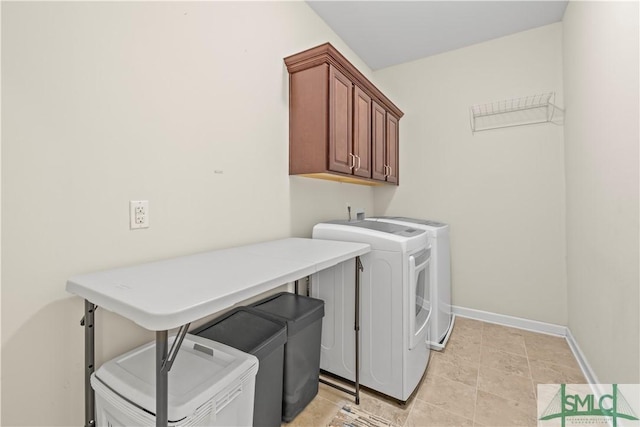 washroom featuring baseboards, cabinet space, and washer and dryer