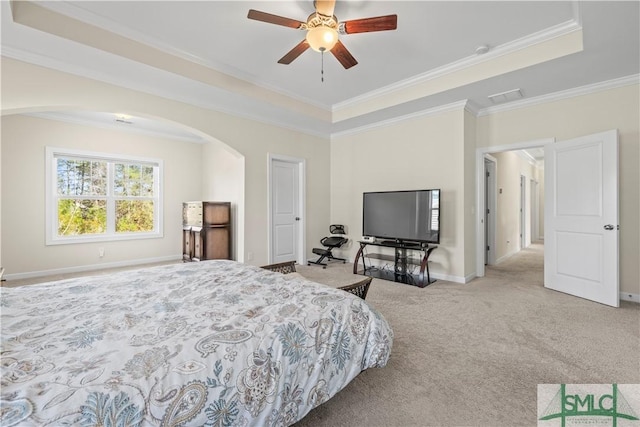 carpeted bedroom with arched walkways, a tray ceiling, and crown molding