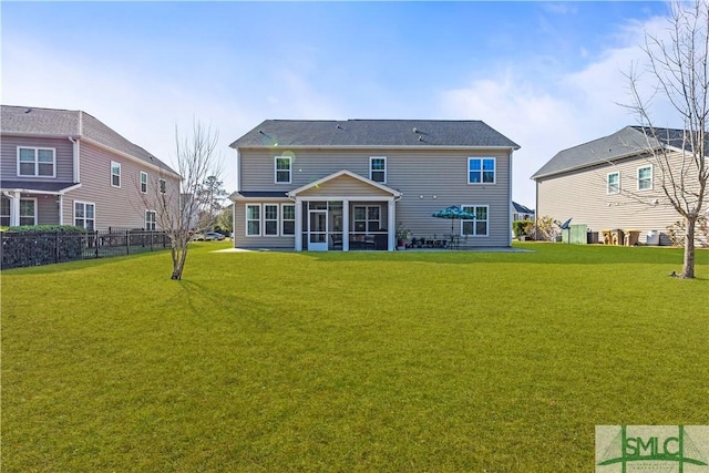 rear view of house with a sunroom, a yard, and fence