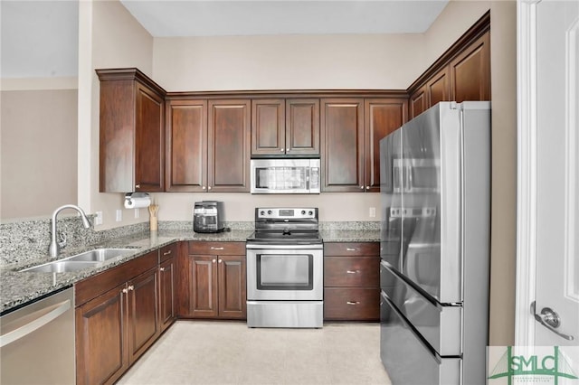 kitchen with light stone counters, stainless steel appliances, and a sink