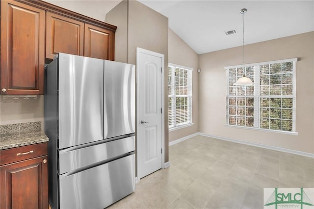 kitchen featuring visible vents, lofted ceiling, freestanding refrigerator, hanging light fixtures, and light stone countertops