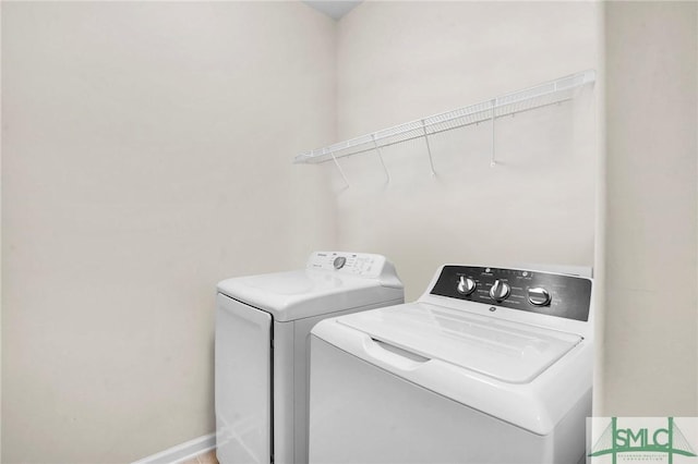 washroom featuring laundry area, baseboards, and washer and clothes dryer