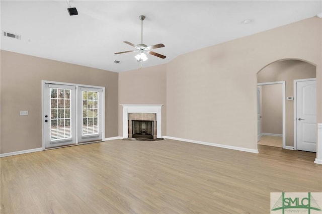 unfurnished living room with light wood finished floors, a tiled fireplace, visible vents, and baseboards