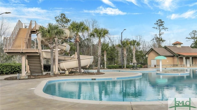 community pool featuring a patio area, a hot tub, and stairway