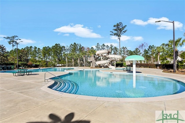 pool featuring a water slide and a patio area