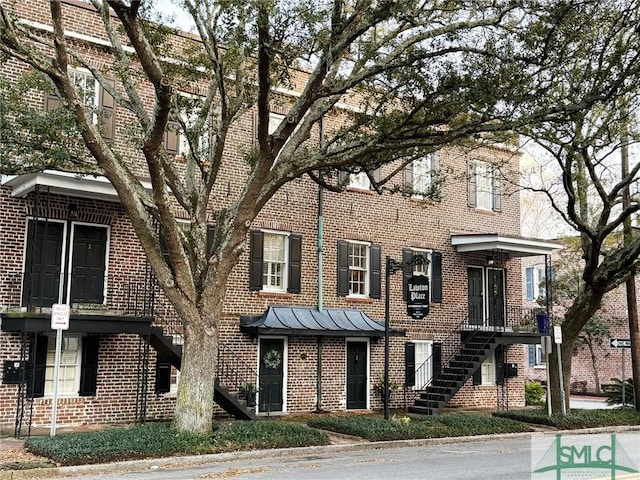 townhome / multi-family property featuring stairs, brick siding, and a standing seam roof