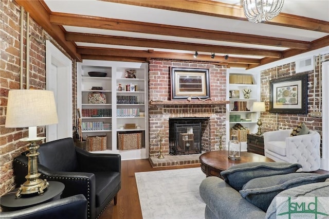 living area with brick wall, a fireplace, wood finished floors, and beam ceiling