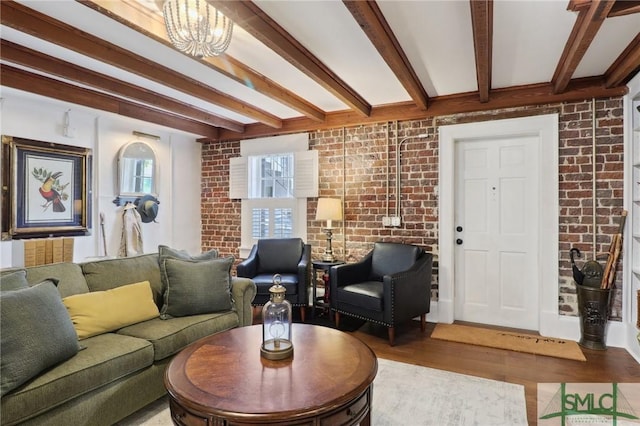 living area featuring brick wall, beam ceiling, and wood finished floors