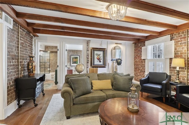 living room with brick wall, wood finished floors, visible vents, beamed ceiling, and a wood stove