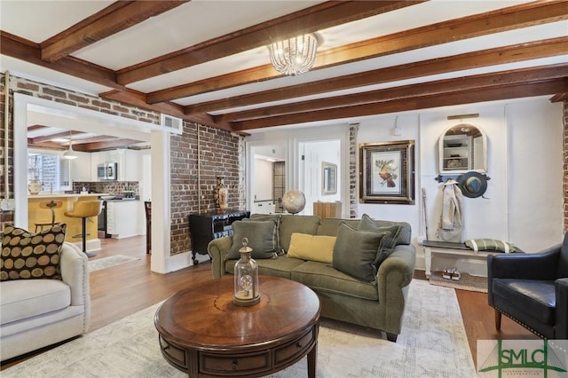 living area featuring light wood-type flooring, brick wall, visible vents, and beam ceiling