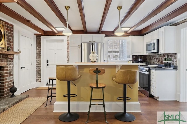 kitchen with a breakfast bar, dark wood-style flooring, pendant lighting, appliances with stainless steel finishes, and white cabinetry