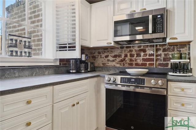 kitchen with appliances with stainless steel finishes, dark countertops, and white cabinetry