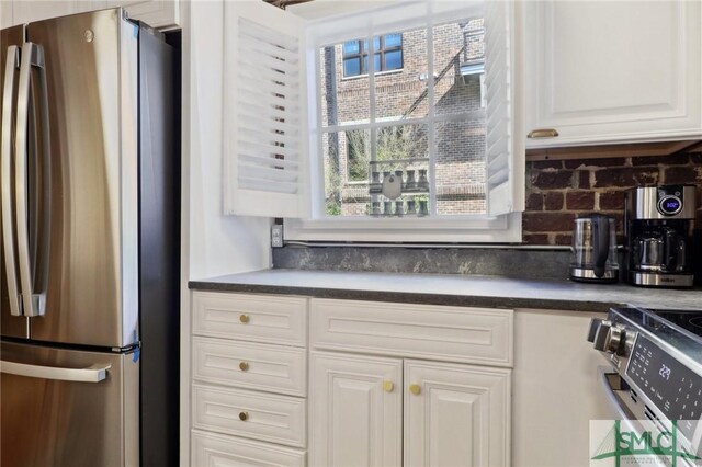 kitchen featuring stainless steel appliances, dark countertops, white cabinets, and tasteful backsplash