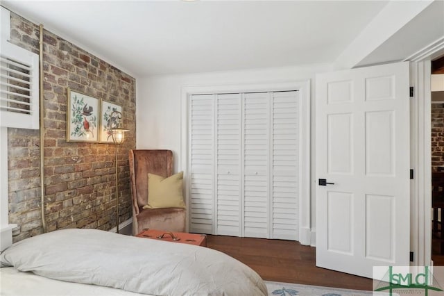 bedroom with brick wall, a closet, and wood finished floors