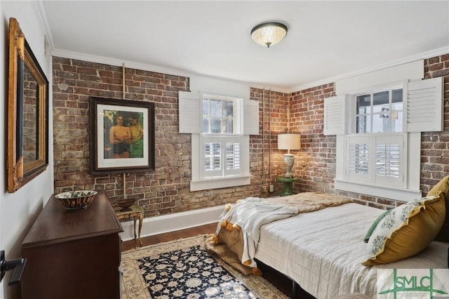 bedroom with crown molding, brick wall, wood finished floors, and baseboards