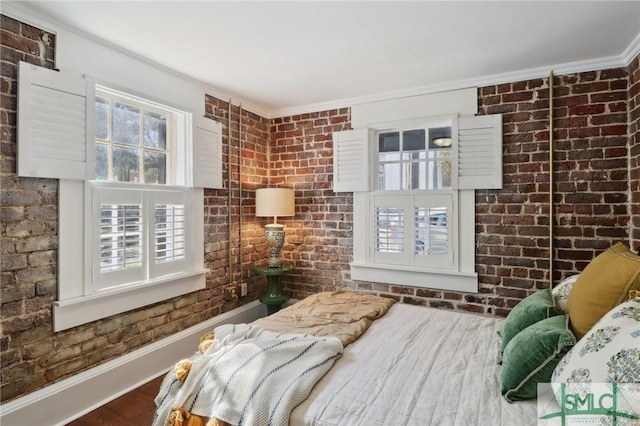 bedroom with baseboards, brick wall, and wood finished floors