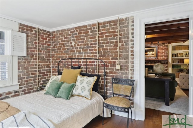 bedroom featuring brick wall, ornamental molding, and wood finished floors