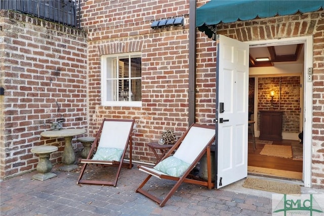 exterior space with brick siding and a patio