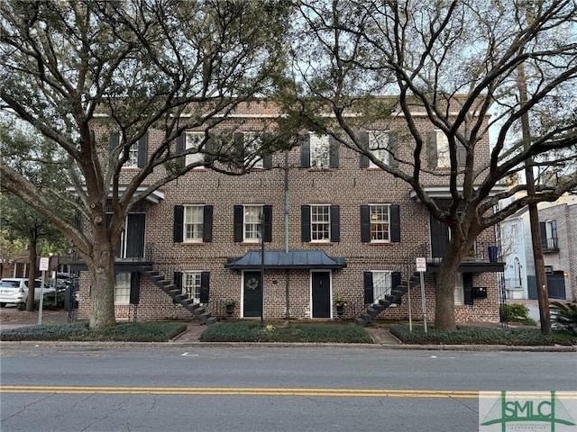 view of property with brick siding and stairway