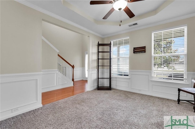 interior space with visible vents, a raised ceiling, ceiling fan, stairs, and carpet floors