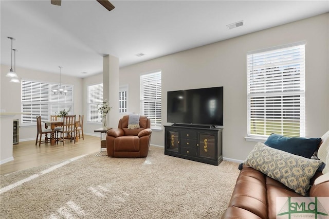 carpeted living room with a ceiling fan, visible vents, and baseboards