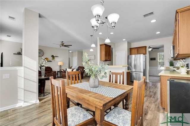 dining room with ceiling fan with notable chandelier, light wood-type flooring, visible vents, and recessed lighting