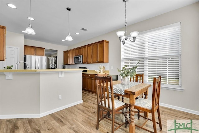 dining space with a notable chandelier, light wood finished floors, recessed lighting, visible vents, and baseboards