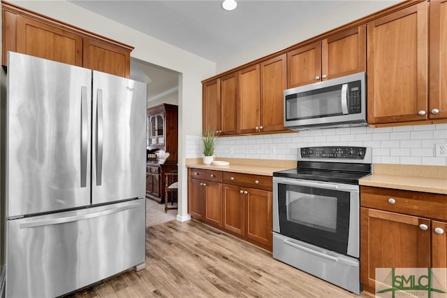 kitchen featuring appliances with stainless steel finishes, light countertops, brown cabinetry, and backsplash