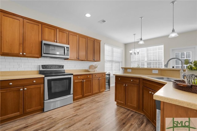 kitchen with visible vents, appliances with stainless steel finishes, brown cabinetry, and a sink