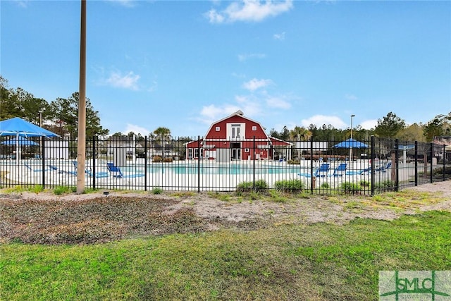 community pool with a barn, fence, and an outbuilding