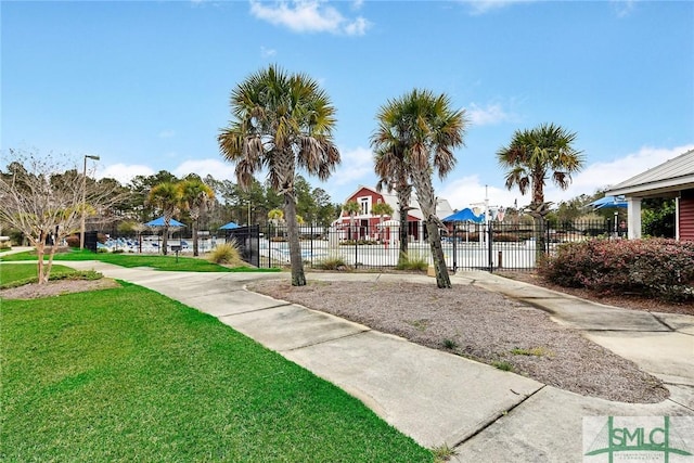 view of property's community with fence and a lawn