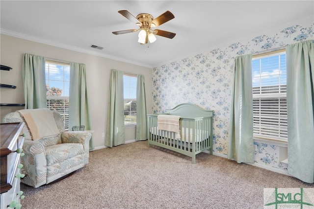 carpeted bedroom with crown molding, visible vents, a ceiling fan, baseboards, and wallpapered walls