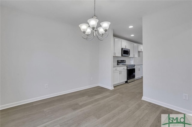 unfurnished dining area with light wood finished floors, recessed lighting, baseboards, and an inviting chandelier