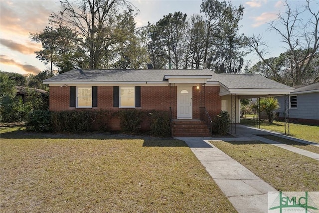 single story home with a carport, brick siding, a front yard, and driveway